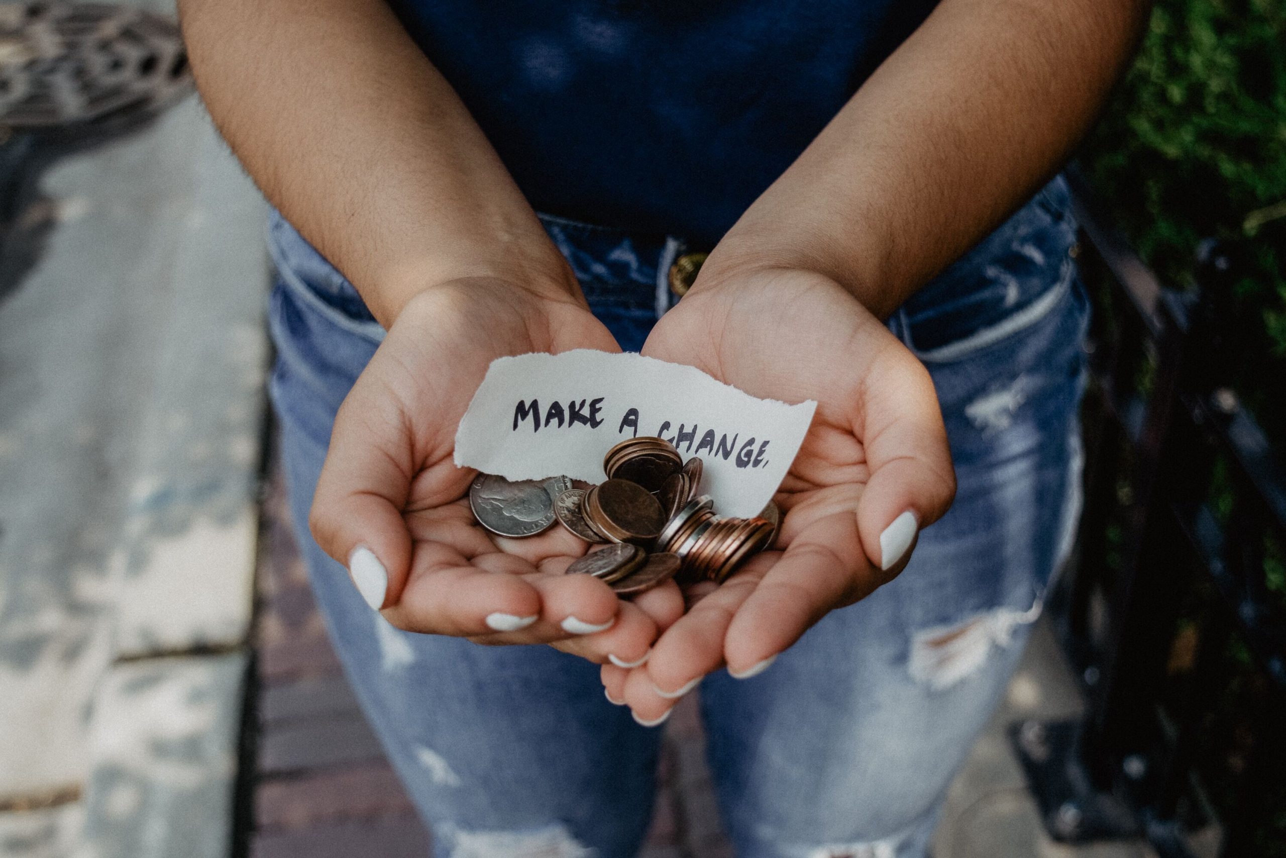 A photograph of a person holding out their hands filled with coins and a message that reads "Make a change"
