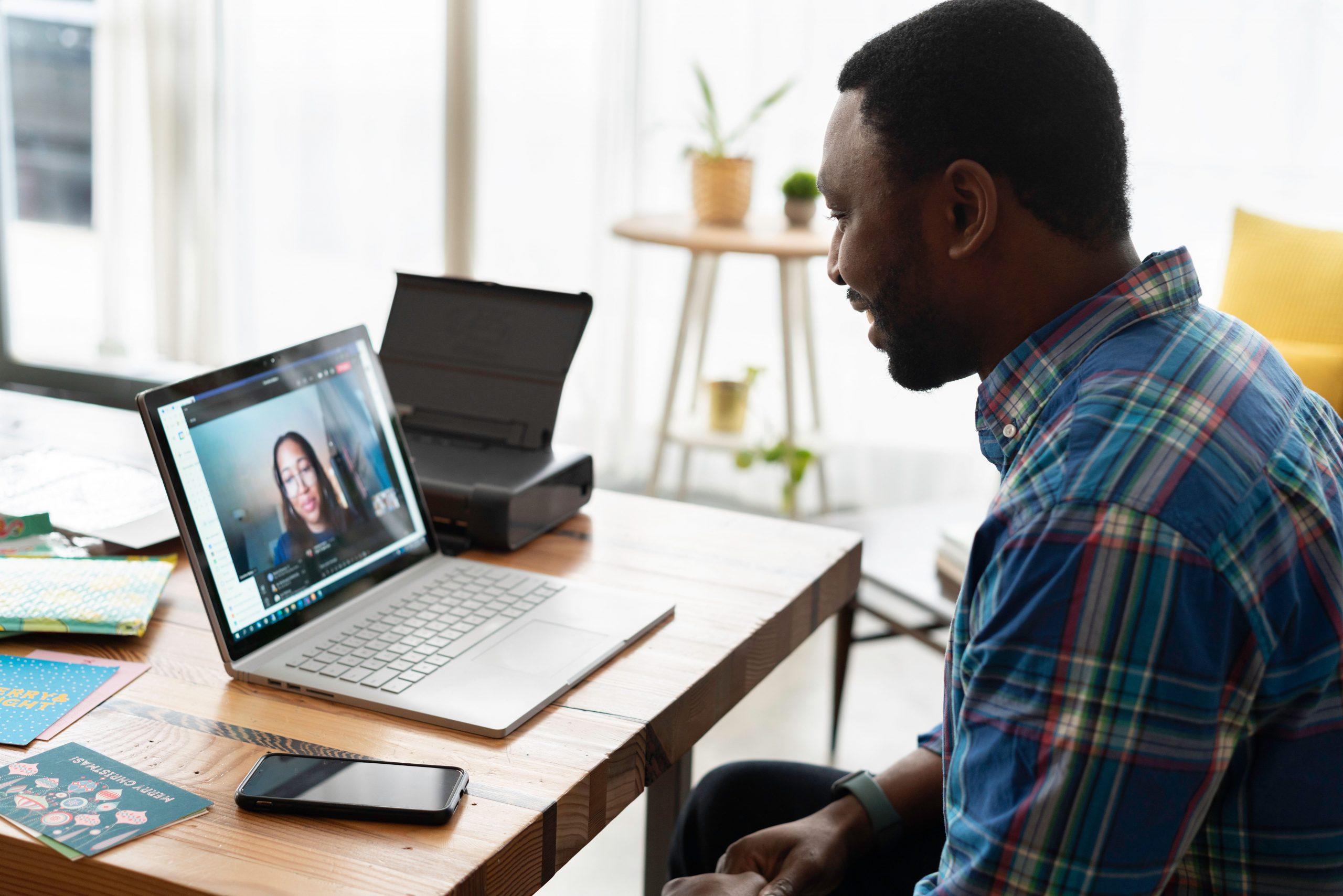 A man looking at a laptop, he appears to be in a video call with a woman.