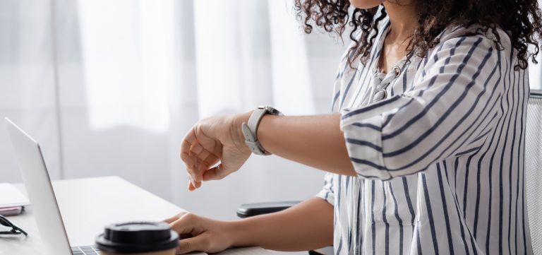 partial view of african american freelancer looking at watch near laptop at home