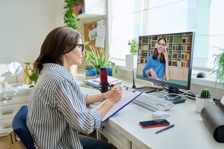 A brown haired woman taking notes whilst attending a webinar session